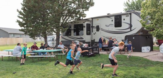 Happy children running by family gathering at Southern Hills RV Park and Campground Smiling children running near family gathering at Southern Hills RV Park and Campground